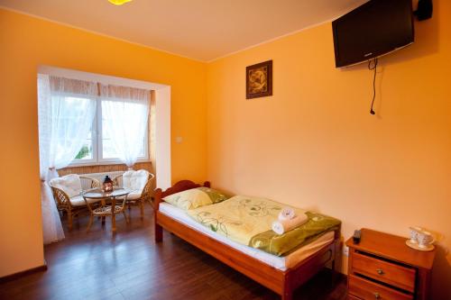 a small bedroom with a bed and a table at Willa Ostoja in Świeradów-Zdrój