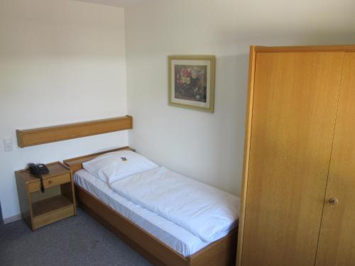 a small bedroom with a small bed and a nightstand at Hotel Waldesruh in Düsseldorf