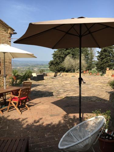 a patio with an umbrella and a table and chairs at Case Nell' Aia in Poggibonsi