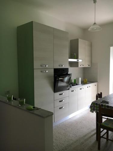 una cucina con mobili bianchi e verdi e un tavolo di Mela Verde a Minturno