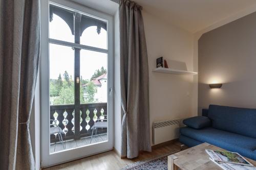 ein Wohnzimmer mit einem blauen Sofa und einer Glasschiebetür in der Unterkunft Herrenhaus am Erlaufsee - DorfResort Mitterbach in Mariazell
