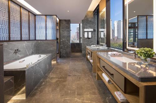 un bagno con 2 lavandini e una vasca di Leshan Ramada Hotel a Leshan