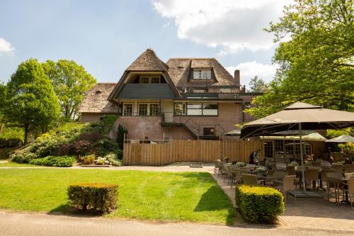 a house with a yard with tables and chairs at Fletcher Hotel Restaurant De Wipselberg-Veluwe in Beekbergen