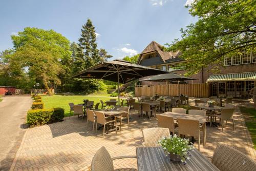 a patio with tables and chairs and an umbrella at Fletcher Hotel Restaurant De Wipselberg-Veluwe in Beekbergen
