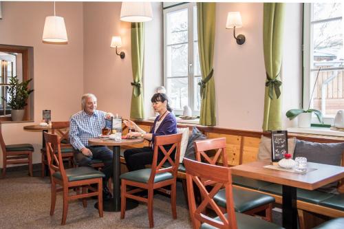 a man and woman sitting at a table in a restaurant at JUFA Hotel Grundlsee in Grundlsee