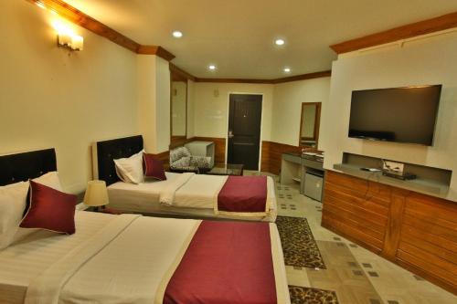 a hotel room with two beds and a flat screen tv at Hotel Gateway Shillong in Shillong