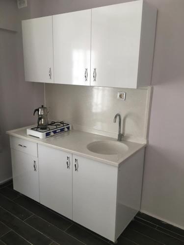 a white kitchen with a sink and a stove at Baskent Otel in Didim