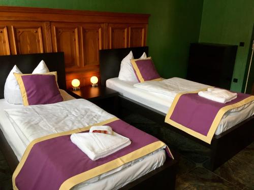 2 Betten in einem Zimmer mit lila und weißen Laken in der Unterkunft Ferienwohnung Alabama in Lutherstadt Wittenberg