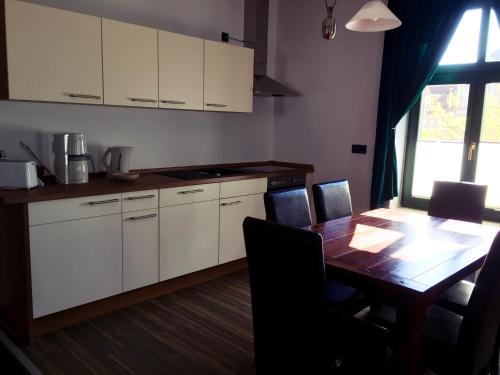 a kitchen with a wooden table and white cabinets at Ferienwohnung Alabama in Lutherstadt Wittenberg