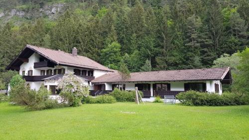 a large house with a yard in front of a forest at Pension Almhof Baumgarten in Bad Reichenhall