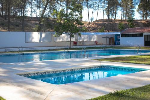 a swimming pool with blue water in a yard at CENTRO DE OCIO ALÚA Bungalows Camping Rafting Benamejí in Benamejí