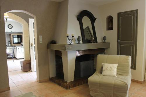 a living room with a fireplace and a chair at Gîtes maisons de vacances Domaine la Chamade Carpentras in Carpentras