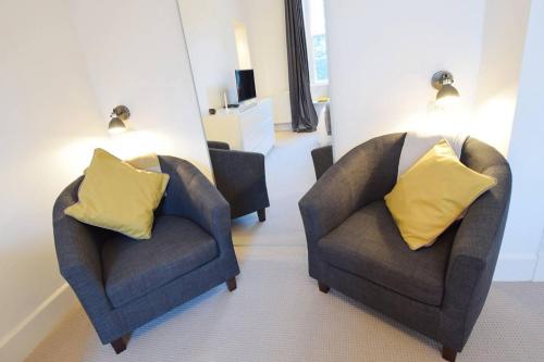two chairs with yellow pillows in a living room at JOIVY Modern City Centre Flat next to Calton Hill in Edinburgh