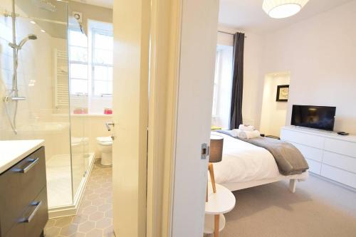 a bedroom with a bed and a bathroom with a shower at JOIVY Modern City Centre Flat next to Calton Hill in Edinburgh