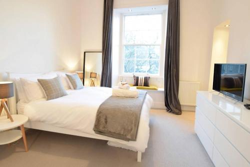 a bedroom with a white bed and a television at JOIVY Modern City Centre Flat next to Calton Hill in Edinburgh