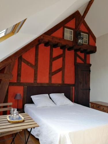 une chambre avec un lit blanc et un mur rouge dans l'établissement Les longères de keridy, à Brech