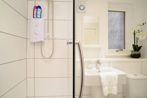 a white bathroom with a shower and a sink at ALTIDO Lovely Apartment for 4 with Free Parking in Edinburgh