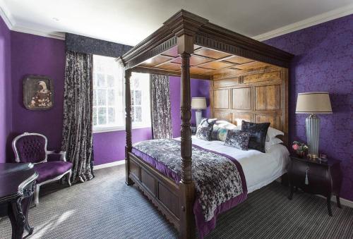 エディンバラにあるJOIVY The Wee Palace by Castleの紫色の壁のベッドルーム1室(天蓋付きベッド1台付)