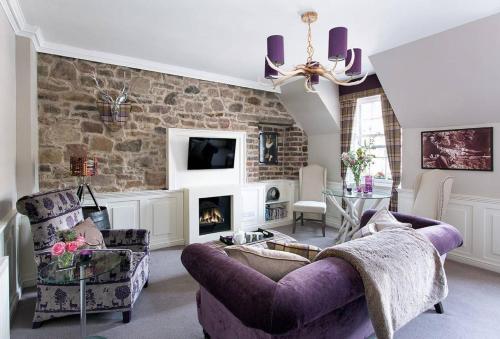 エディンバラにあるJOIVY The Wee Palace by Castleの紫色のソファと暖炉付きのリビングルーム
