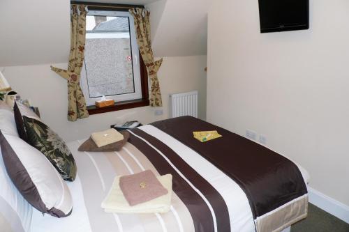 a bedroom with a bed with brown and white sheets and a window at Torridon Guest House in Inverness