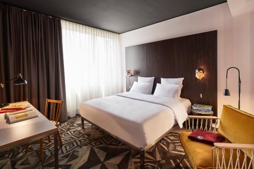 a hotel room with a large white bed and a desk at Mama Shelter Prague in Prague