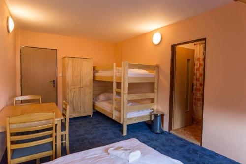 a room with a bed and a table and bunk beds at Penzion Šatovské lípy in Šatov