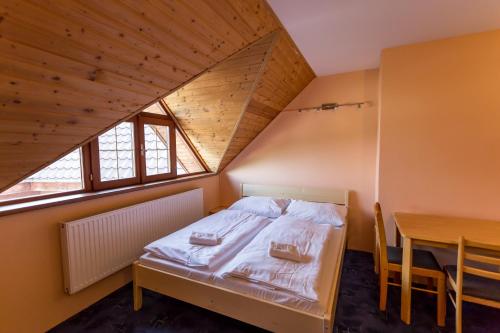 a small bedroom with a bed and a table at Penzion Šatovské lípy in Šatov