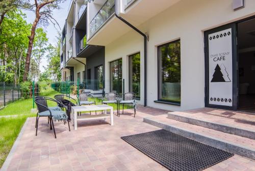 a patio with chairs and a table in front of a building at Dwie Sosny z sauną, Sun & Snow in Ustronie Morskie