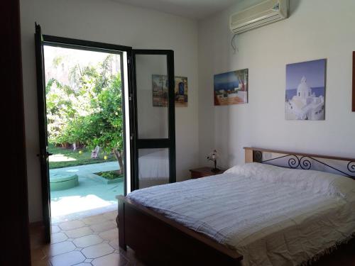 a bedroom with a bed and a sliding glass door at Villa Angela in Marinella di Selinunte