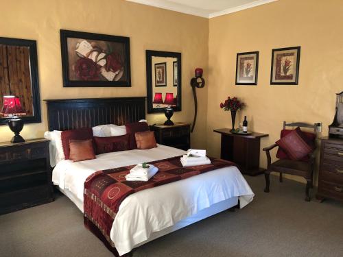 a hotel room with a bed, desk, chair, and lamp at Dio Dell Amore Guest House in Jeffreys Bay