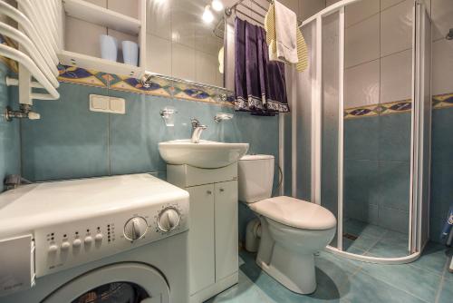 y baño con aseo, lavabo y lavadora. en Vanagas Apartments en Palanga