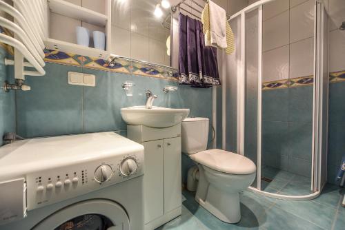 a bathroom with a toilet and a sink and a washing machine at Vanagas Apartments in Palanga