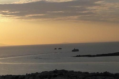 a group of rocks in the water at sunset at Amazing Sea View Villa in Parikia