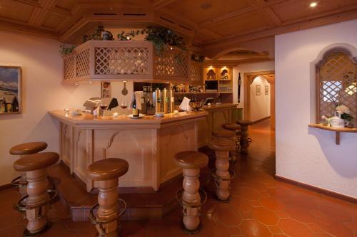 a kitchen with a bar with stools in a room at Hotel Omesberg in Lech am Arlberg