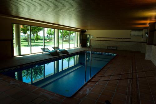 a swimming pool in a building with a large window at La Noguera Camping in Sant Llorenç de Montgai