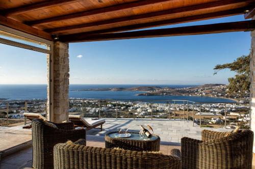 a patio with chairs and a table and a view of the ocean at Amazing Sea View Villa in Parikia