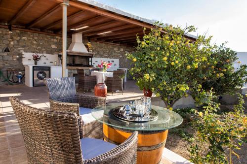 a patio with a glass table and chairs and a fireplace at Amazing Sea View Villa in Parikia