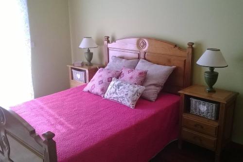um quarto com uma cama rosa com almofadas em Moradia em condomínio de luxo em Esposende