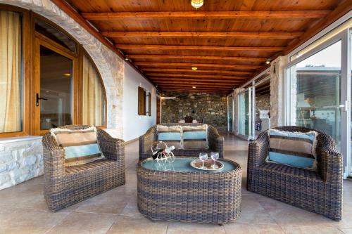 a porch with three wicker chairs and a table at Amazing Sea View Villa in Parikia