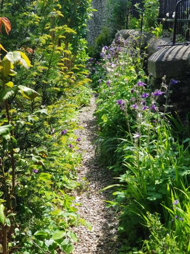 a path in a garden with purple flowers at The Hand Hotel Llangollen by Compass Hospitality in Llangollen