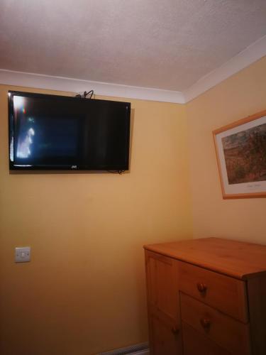a flat screen tv on the wall of a bedroom at Granville Guest House in Dyce