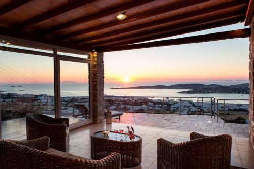 a patio with chairs and a table and a sunset at Amazing Sea View Villa in Parikia