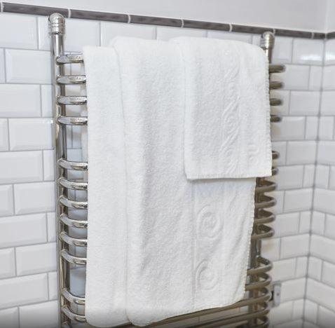 a towel rack with white towels hanging in a bathroom at Hunters Hall Inn by Greene King Inns in Kingscote