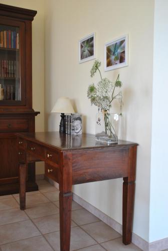 a wooden desk with a vase of flowers on it at Casa Sa serra in Lotzorai