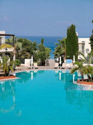a large blue swimming pool with the ocean in the background at Louis Paphos Breeze in Paphos City