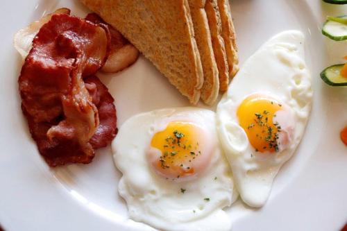 a white plate with eggs bacon bacon and toast at Augrabies Falls Lodge & Camp in Augrabies