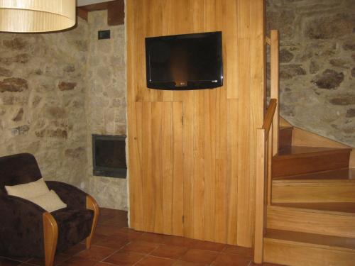 a living room with a tv and a stair case at Ares do Montemuro in Campo Benfeito
