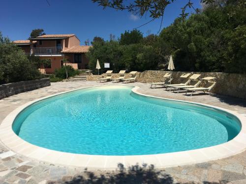 a swimming pool in a yard with chairs and a house at Hotel Belvedere in Teulada