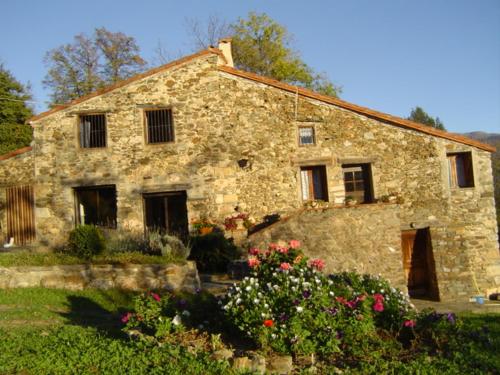 une ancienne maison en pierre avec des fleurs devant elle dans l'établissement El Casal, à Prats-de-Mollo-la-Preste