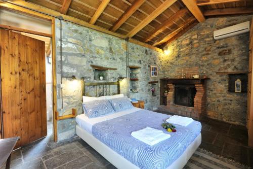 a bedroom with a bed and a stone wall at Gera's Olive Grove - Elaionas Lesvou in Perama